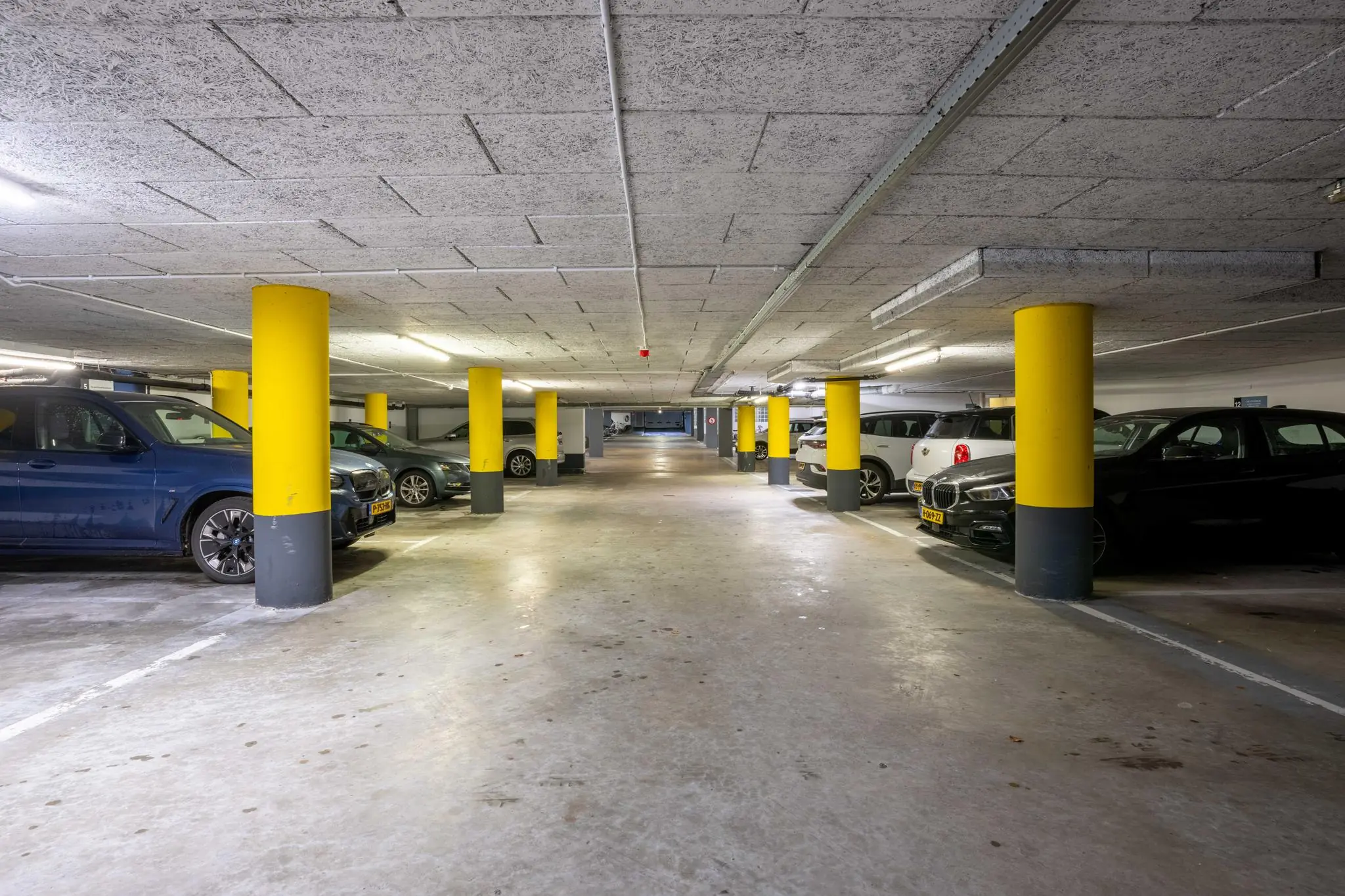 Ondergrondse parkeergarage met geparkeerde auto's en gele kolommen aan de 1e Hogeweg.